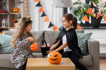 Image showing girls in halloween costumes with candies at home