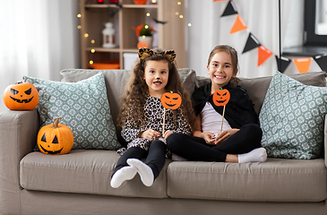 Image showing girls in halloween costumes with pumpkins at home