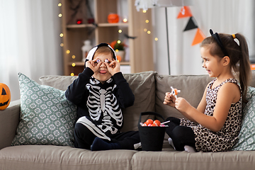 Image showing kids in halloween costumes with candies at home