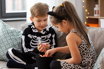 Image showing kids in halloween costumes with candies at home