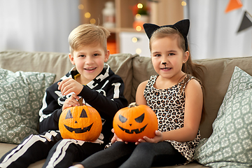 Image showing kids in halloween costumes with pumpkins at home