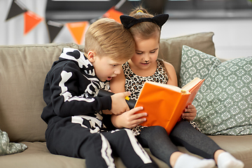 Image showing kids in halloween costumes reading book at home