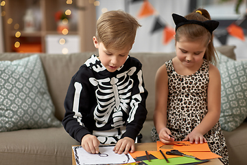 Image showing kids in halloween costumes doing crafts at home