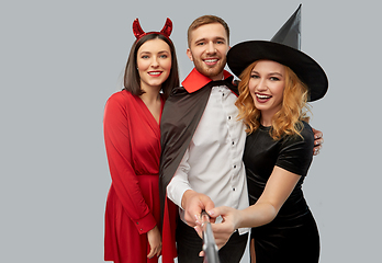 Image showing happy friends in halloween costumes taking selfie