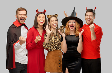 Image showing happy friends in halloween costumes over grey