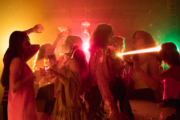 Image showing A crowd of people in silhouette raises their hands on dancefloor on neon light background