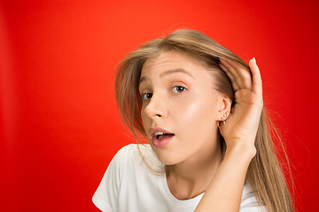 Image showing Portrait of young caucasian woman with bright emotions on bright red studio background