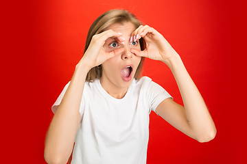 Image showing Portrait of young caucasian woman with bright emotions on bright red studio background