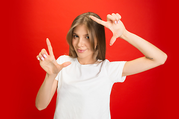 Image showing Portrait of young caucasian woman with bright emotions on bright red studio background