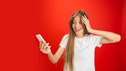 Image showing Portrait of young caucasian woman with bright emotions on bright red studio background