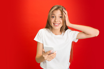 Image showing Portrait of young caucasian woman with bright emotions on bright red studio background