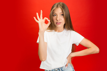 Image showing Portrait of young caucasian woman with bright emotions on bright red studio background