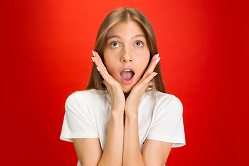 Image showing Portrait of young caucasian woman with bright emotions on bright red studio background