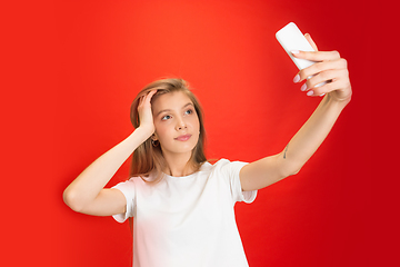 Image showing Portrait of young caucasian woman with bright emotions on bright red studio background