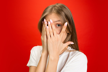 Image showing Portrait of young caucasian woman with bright emotions on bright red studio background