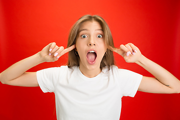 Image showing Portrait of young caucasian woman with bright emotions on bright red studio background