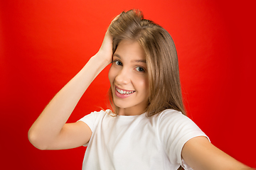 Image showing Portrait of young caucasian woman with bright emotions on bright red studio background