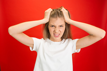 Image showing Portrait of young caucasian woman with bright emotions on bright red studio background