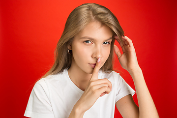 Image showing Portrait of young caucasian woman with bright emotions on bright red studio background