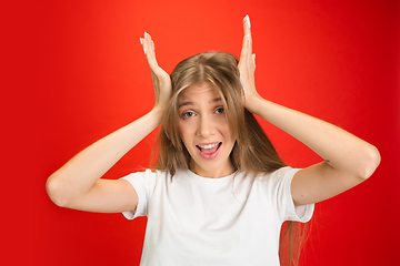 Image showing Portrait of young caucasian woman with bright emotions on bright red studio background