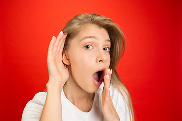 Image showing Portrait of young caucasian woman with bright emotions on bright red studio background