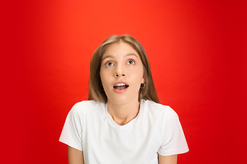 Image showing Portrait of young caucasian woman with bright emotions on bright red studio background