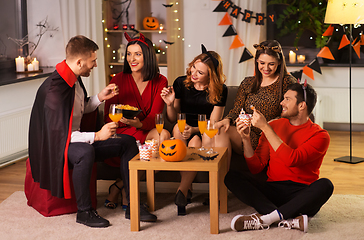 Image showing happy friends in halloween costumes at home party