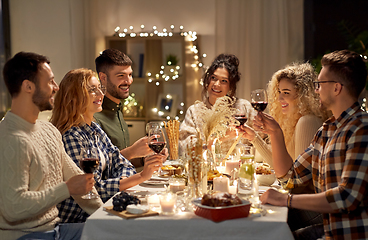 Image showing happy friends drinking red wine at christmas party