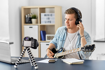 Image showing man or blogger with camera playing guitar at home