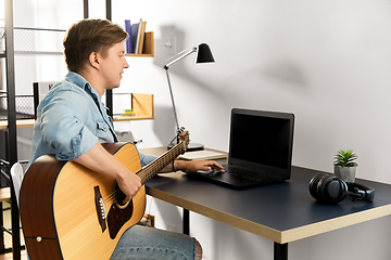 Image showing young man with laptop and guitar at home