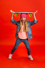 Image showing Caucasian little girl portrait isolated on red studio background. Cute stylish model