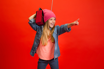 Image showing Caucasian little girl portrait isolated on red studio background. Cute stylish model