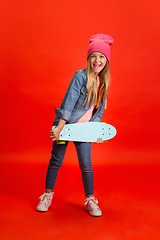 Image showing Caucasian little girl portrait isolated on red studio background. Cute stylish model