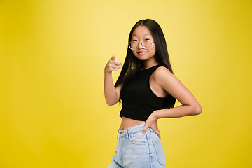 Image showing Portrait of young asian girl isolated on yellow studio background