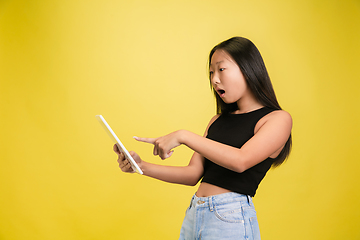 Image showing Portrait of young asian girl isolated on yellow studio background