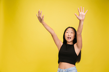 Image showing Portrait of young asian girl isolated on yellow studio background