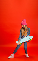 Image showing Caucasian little girl portrait isolated on red studio background. Cute stylish model