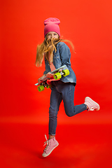 Image showing Caucasian little girl portrait isolated on red studio background. Cute stylish model