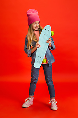 Image showing Caucasian little girl portrait isolated on red studio background. Cute stylish model