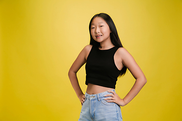 Image showing Portrait of young asian girl isolated on yellow studio background