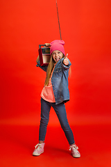 Image showing Caucasian little girl portrait isolated on red studio background. Cute stylish model