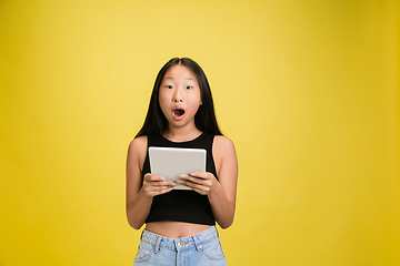 Image showing Portrait of young asian girl isolated on yellow studio background