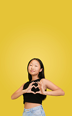 Image showing Portrait of young asian girl isolated on yellow studio background