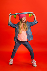 Image showing Caucasian little girl portrait isolated on red studio background. Cute stylish model