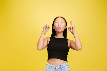 Image showing Portrait of young asian girl isolated on yellow studio background