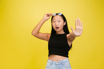 Image showing Portrait of young asian girl isolated on yellow studio background