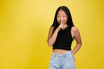 Image showing Portrait of young asian girl isolated on yellow studio background