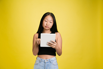 Image showing Portrait of young asian girl isolated on yellow studio background