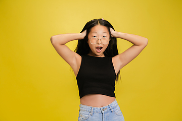 Image showing Portrait of young asian girl isolated on yellow studio background