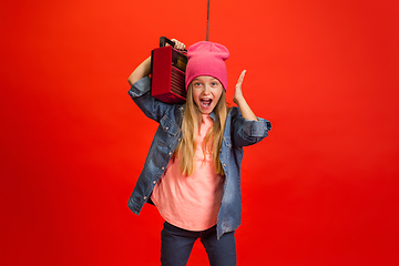 Image showing Caucasian little girl portrait isolated on red studio background. Cute stylish model